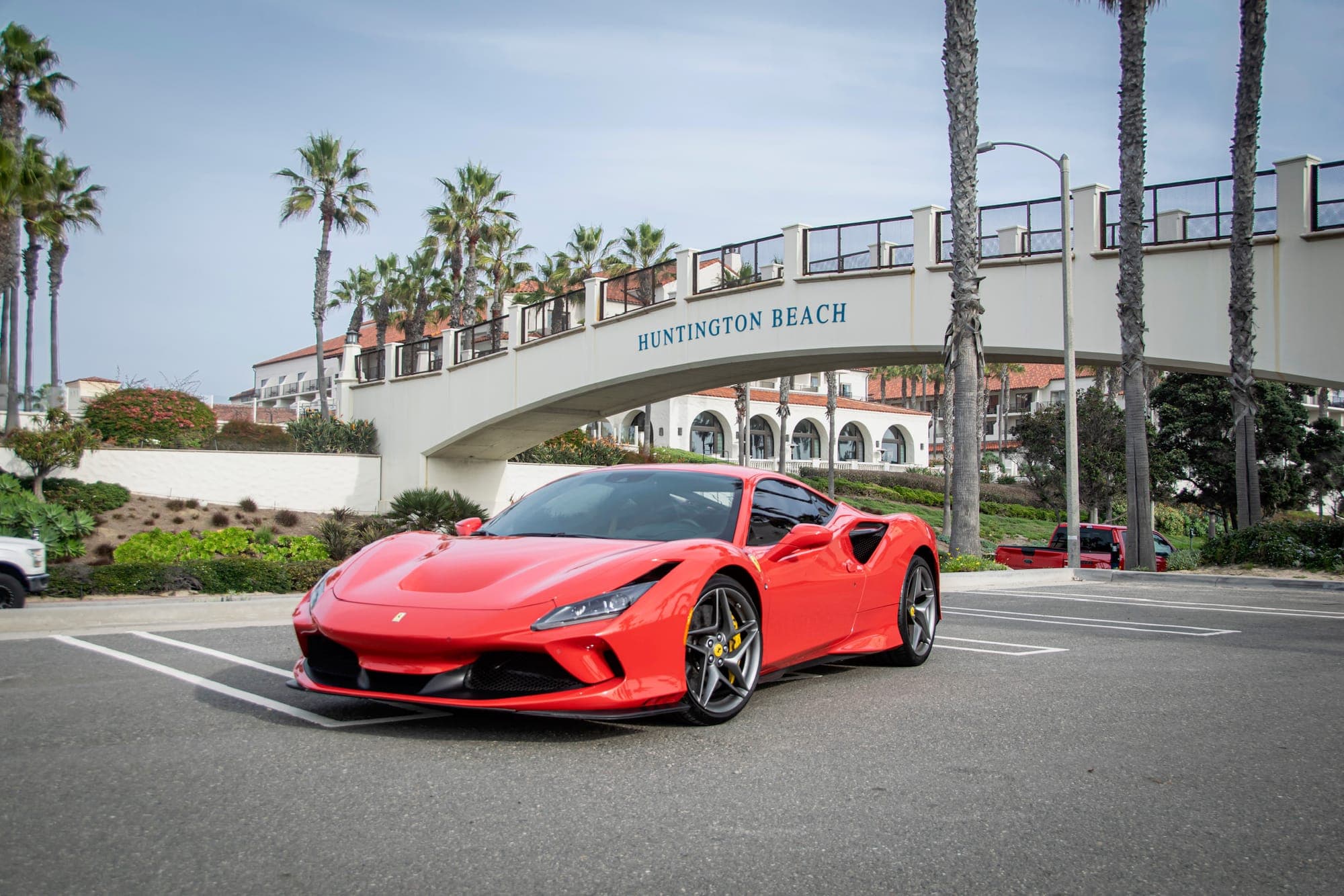 Red Ferrari F8 Spider parked near the Huntington Beach pier