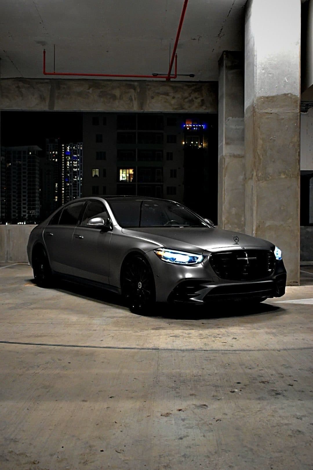 Mercedes-Benz sedan with headlights on in a private garage at night